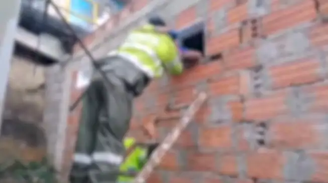 En Medellín, un policía sube por escaleras hasta una ventana para rescatar a un niño de 5 años encerrado